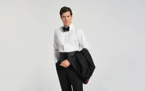 Mann im Smoking mit Fliege und Kummerbund, bereit für den black tie dresscode herren.