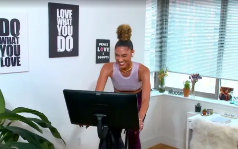 Frau lacht auf einem Heimtrainer, bereit für ein intensives Tabata Workout. Wandbilder motivieren: "Do what you love".
