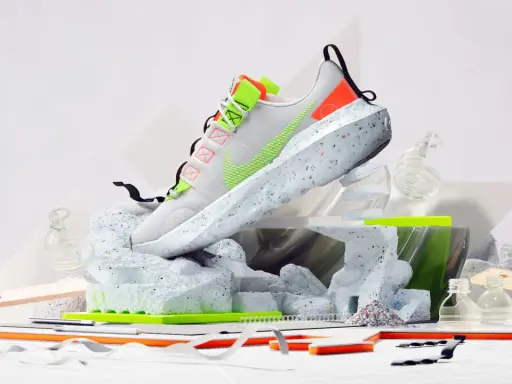 Nike Move to Zero: Ein weißer Schuh mit neongrünen Akzenten, der auf einer skulpturalen Basis aus recyceltem Material steht.