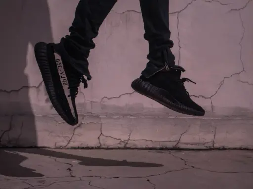 Schwarze Yeezy binden, die in der Luft schweben, mit einem Streifen auf der Seite.