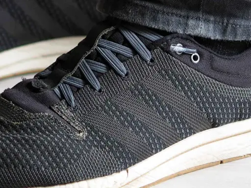 Schuhe binden ohne schleife: Schnürsenkel sind durch Ösen geführt und mit einem Stopper fixiert, was schnelles Anziehen ermöglicht.