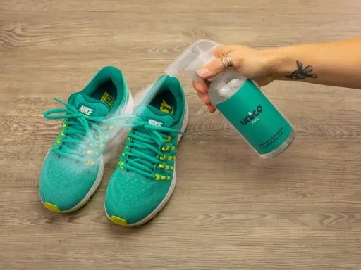 Grüne Nike-Laufschuhe werden mit einem Spray besprüht, um zu verhindern, dass die schuhe stinken. Was tun?