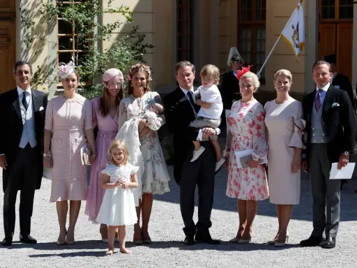 Familie in festlicher Kleidung, die überlegt, was anziehen zur Taufe. Ein Mann trägt ein Baby, Kinder und Frauen in eleganten Kleidern.