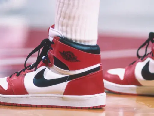 Die ersten Jordan Schuhe, rot-weiß-schwarz, auf einem Basketballfeld. Ein ikonischer Sneaker-Moment.
