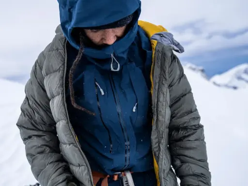 Person in Daunenjacke im Schnee. Tipps zum daunenjacke waschen für optimale Wärme.