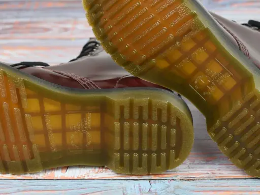 Die charakteristische, gelbe Naht und das Profil der **Dr. Martens Sohle original** sind auf dem Holzuntergrund zu sehen.