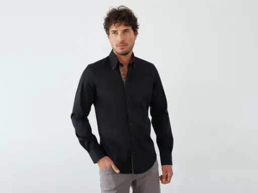 Mann in schwarzem Hemd mit farbigem Kragen und grauer Hose. Ein stilvoller Look, wie man ein schwarzes Hemd kombinieren kann.