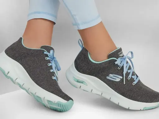 Graue Skechers-Sneaker mit hellblauen Schnürsenkeln und mintgrünen Akzenten. Die Sohlen zeigen die Skechers Sohlen Unterschiede, mit einer markanten ArchFit-Technologie.