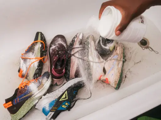 Mehrere Laufschuhe werden in einer Wanne mit einem Pulver bestreut, um sie zu reinigen und zu desinfizieren.
