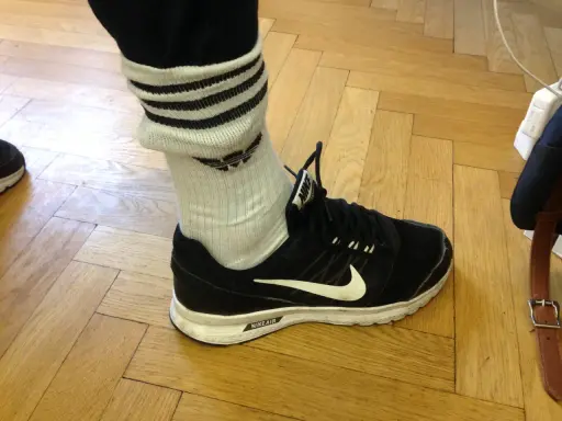 Schwarzer Nike-Schuh mit weißen Streifen an den Socken, die über den Knöchel reichen.