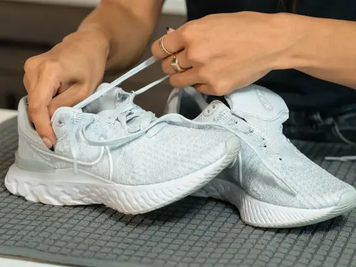 Hände ziehen Schnürsenkel durch hellblaue Mesh Schuhe. So einfach lassen sich die Lieblingssneaker reinigen.