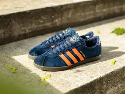 Adidas City Series: dunkelblaue Sneaker mit orangefarbenen Streifen und "Shanghai"-Schriftzug, perfekt für urbane Entdecker.