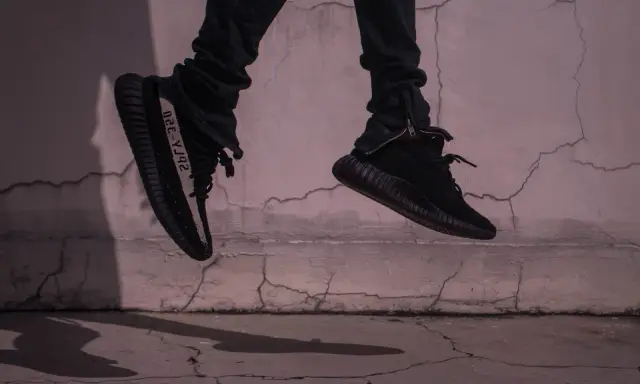 Schwarze Yeezy binden, die in der Luft schweben, mit einem Streifen auf der Seite.