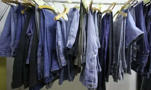 Eine Reihe von Jeans hängt an Kleiderbügeln. Manche sind hellblau, andere dunkelblau. Sie sind bereit, um sie bei 60 Grad zu waschen.
