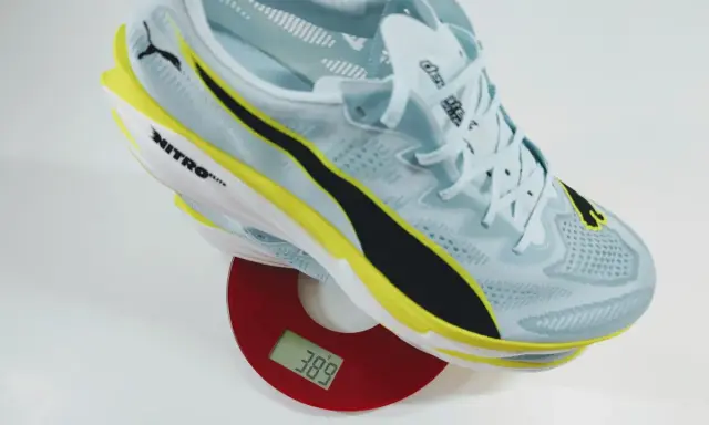 Leichter Laufschuh in Hellblau mit gelben und schwarzen Akzenten auf einer Waage. Das Gewicht der Schuhe beträgt 389 Gramm.