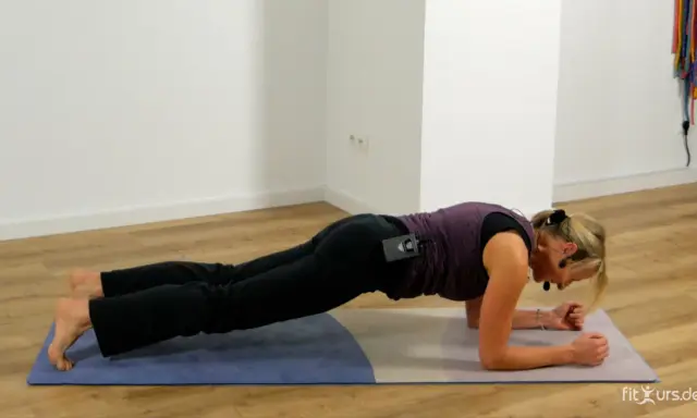 Frau in Unterarmstütz-Position auf einer Matte.