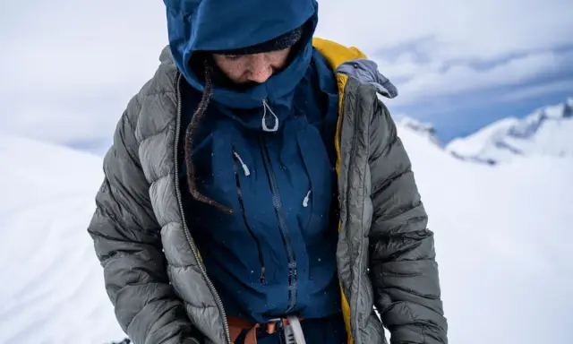 Person in Daunenjacke im Schnee. Tipps zum daunenjacke waschen für optimale Wärme.
