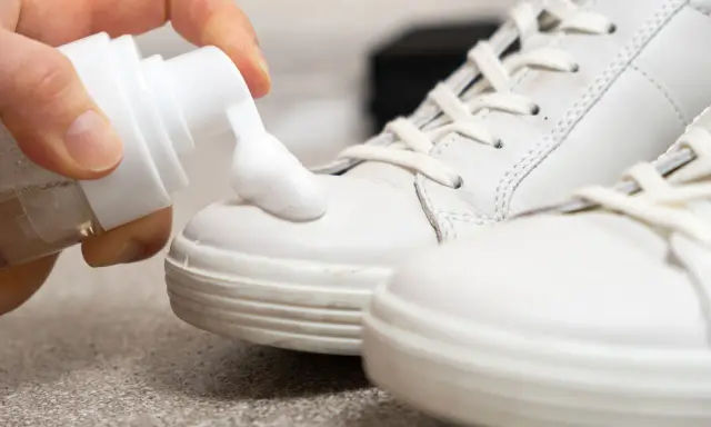Schaum wird auf weiße Sneaker aufgetragen, um sie sauber zu machen.