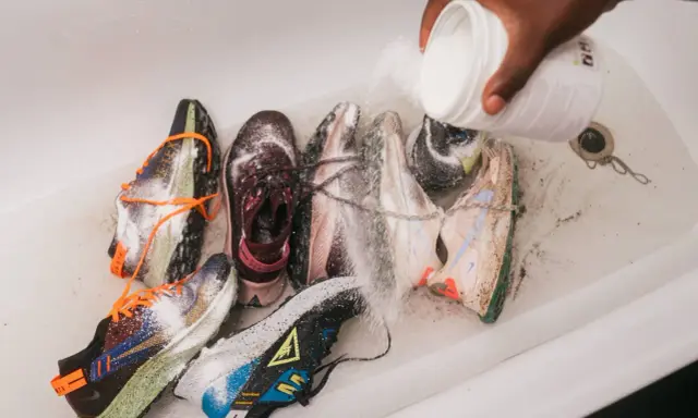 Mehrere Laufschuhe werden in einer Wanne mit einem Pulver bestreut, um sie zu reinigen und zu desinfizieren.