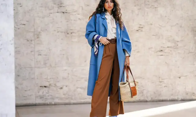 Stilvolles Outfit: Blaue Oversize-Jacke, cremefarbene Bluse mit Schleife und braune weite Hose kombinieren. Accessoires: Korbtasche, Gürtel, Halstuch.