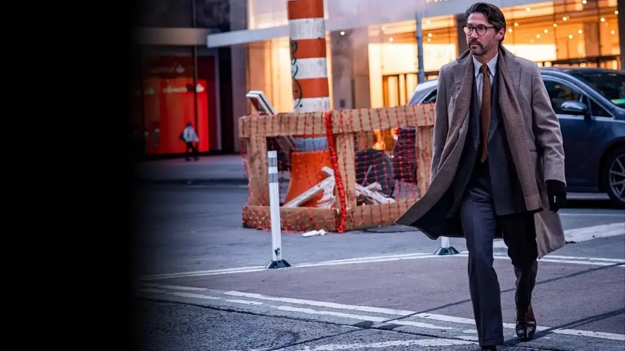 Ein Mann im Business-Casual-Look geht durch die Stadt. Er trägt einen langen Mantel, Anzug und Krawatte.