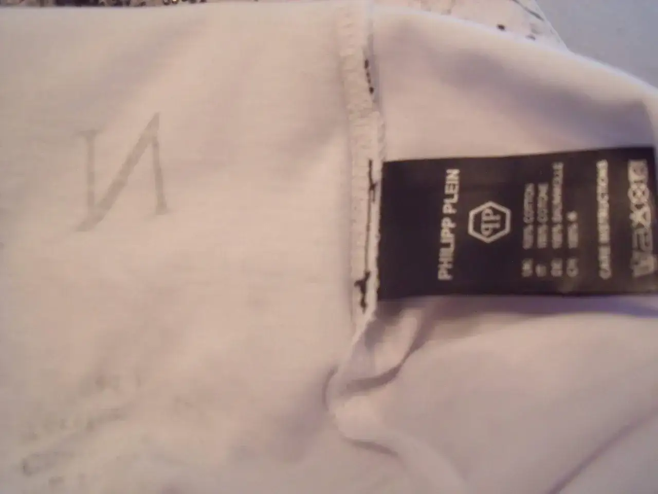 Ein Etikett von Philipp Plein auf einem weißen T-Shirt. Hilft, ein Philipp Plein Fake zu erkennen.