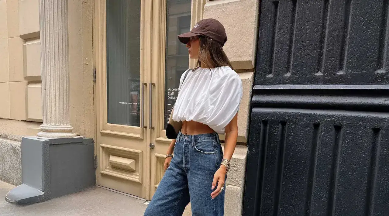 Frau mit brauner Cap richtig tragen, weißes Crop-Top und Jeans.