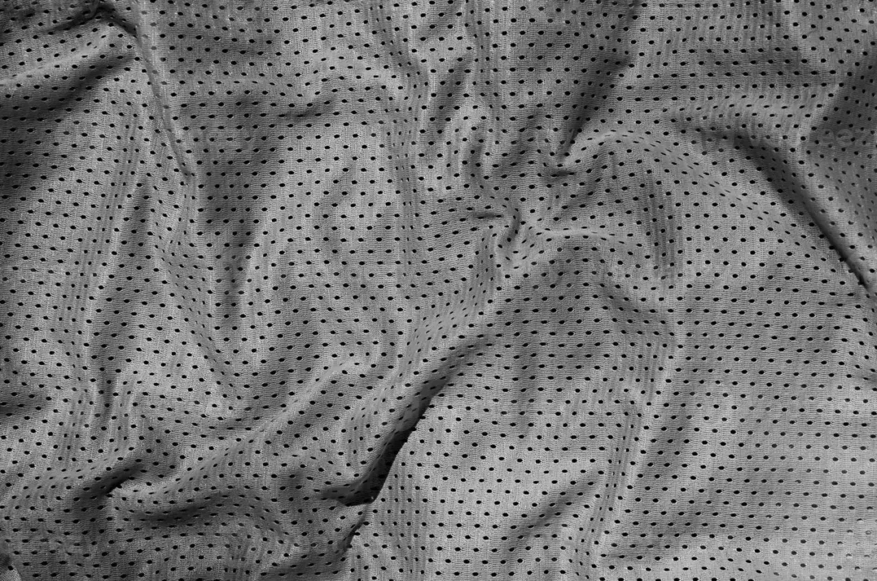 Graues, perforiertes Polyester-Material mit Falten.