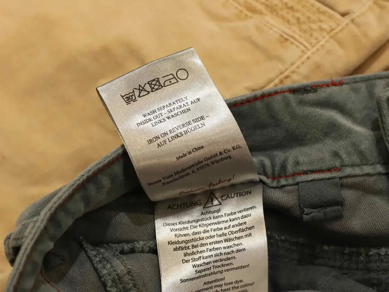 Pflegeetikett zeigt, dass die Jeans bei 30 Grad gewaschen werden soll, nicht bei 60. Separate Wäsche und auf links bügeln empfohlen.