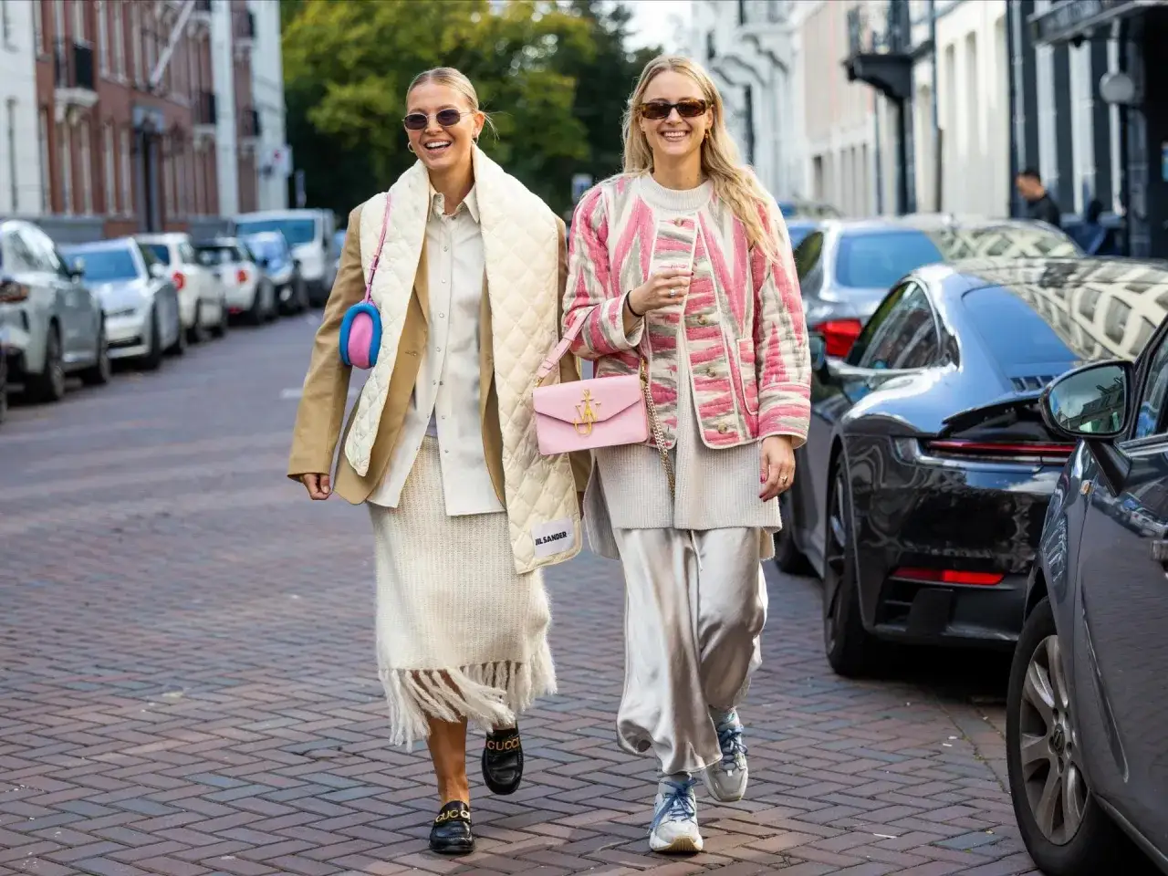Zwei Frauen in stylischen Outfits, perfekt, um was anziehen bei 15 grad. Sie tragen Blazer, Strickröcke und seidige Hosen.