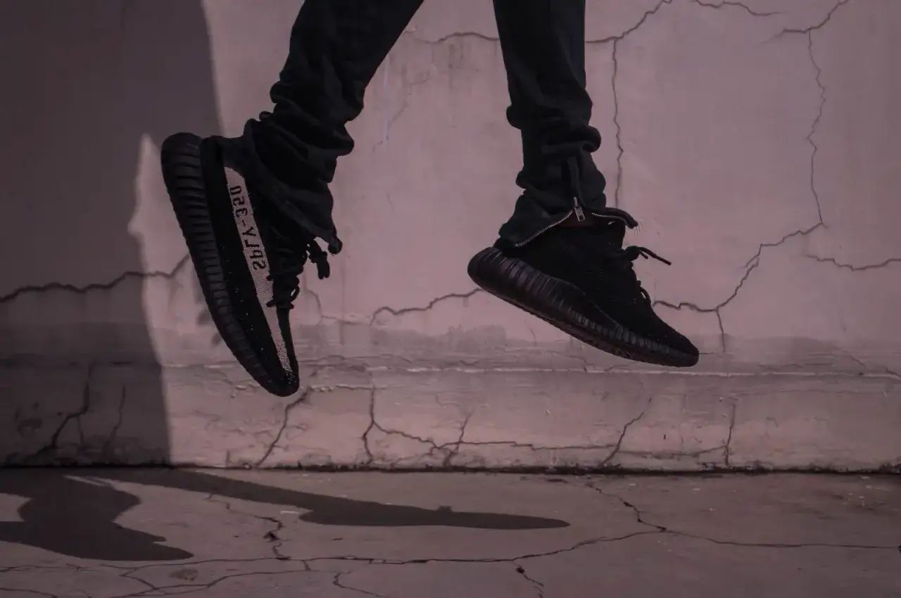 Schwarze Yeezy binden, die in der Luft schweben, mit einem Streifen auf der Seite.