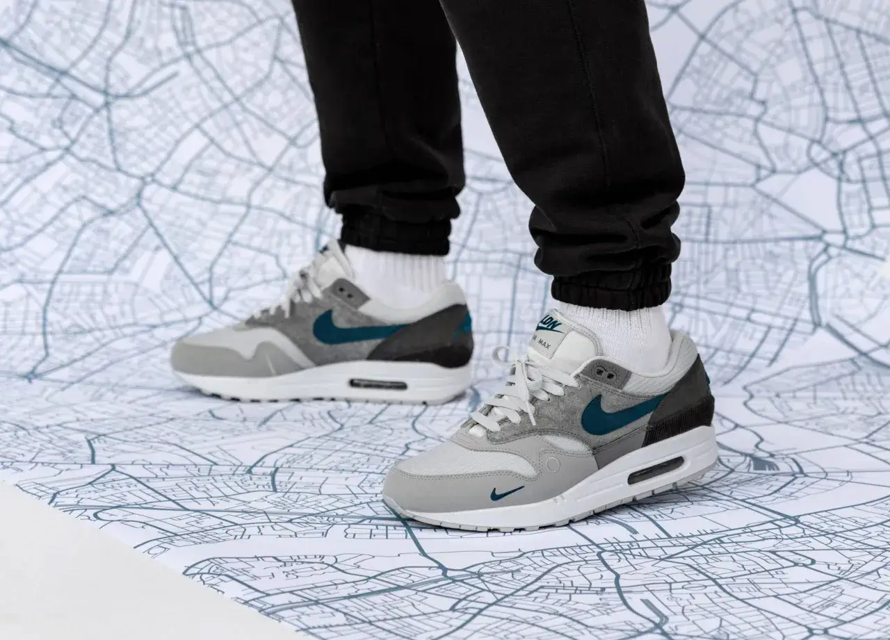 Graue Nike Air Max 1 Sneaker mit türkisfarbenem Swoosh auf einer Stadtkarte. Perfekt für den nächsten air max 1 release.