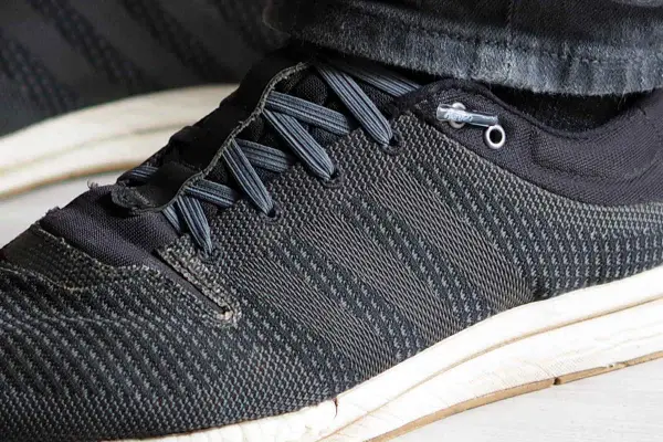 Schuhe binden ohne schleife: Schnürsenkel sind durch Ösen geführt und mit einem Stopper fixiert, was schnelles Anziehen ermöglicht.
