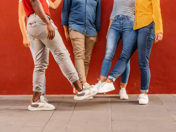 Vier Personen mit stylischen Sneakern stoßen ihre Füße aneinander. Perfekt für einen Sneaker-Blog!