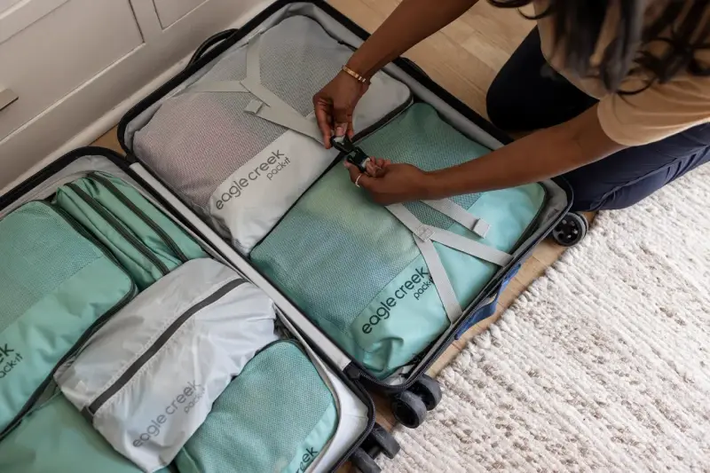 Frau packt ihren Koffer mit Packwürfeln. So packe ich meinen Koffer für die Reise, ordentlich und platzsparend.